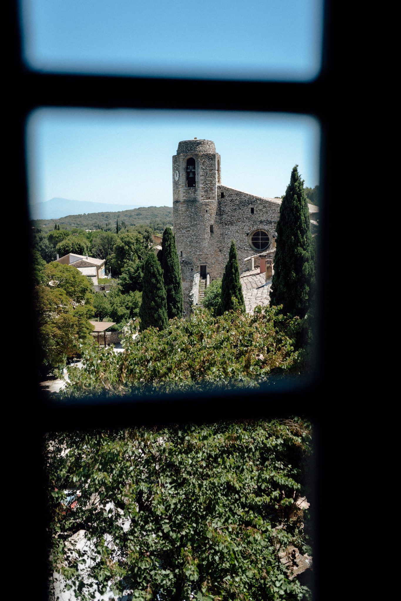 Stone tower of a village chapel seen through a window in Provence