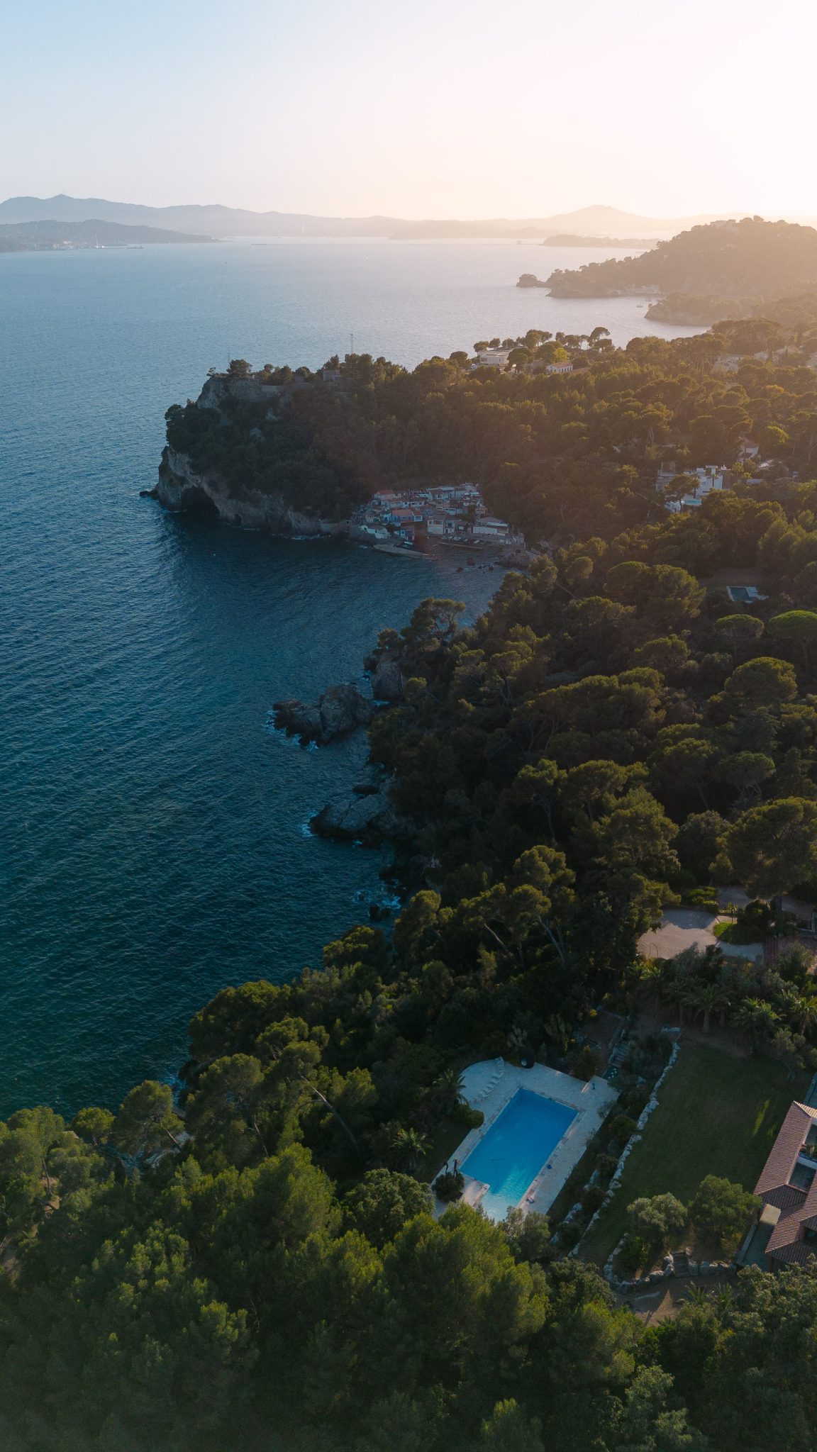 Aerial view of the coast and the villa pool at golden hour