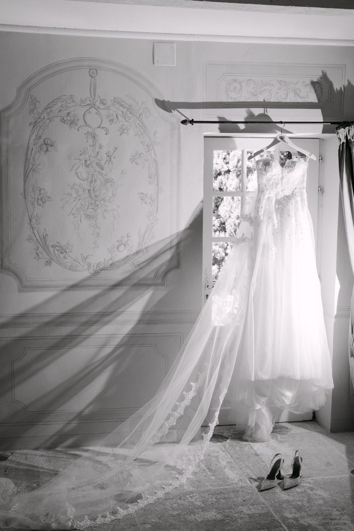 Wedding dress and long veil by a tall window, black and white