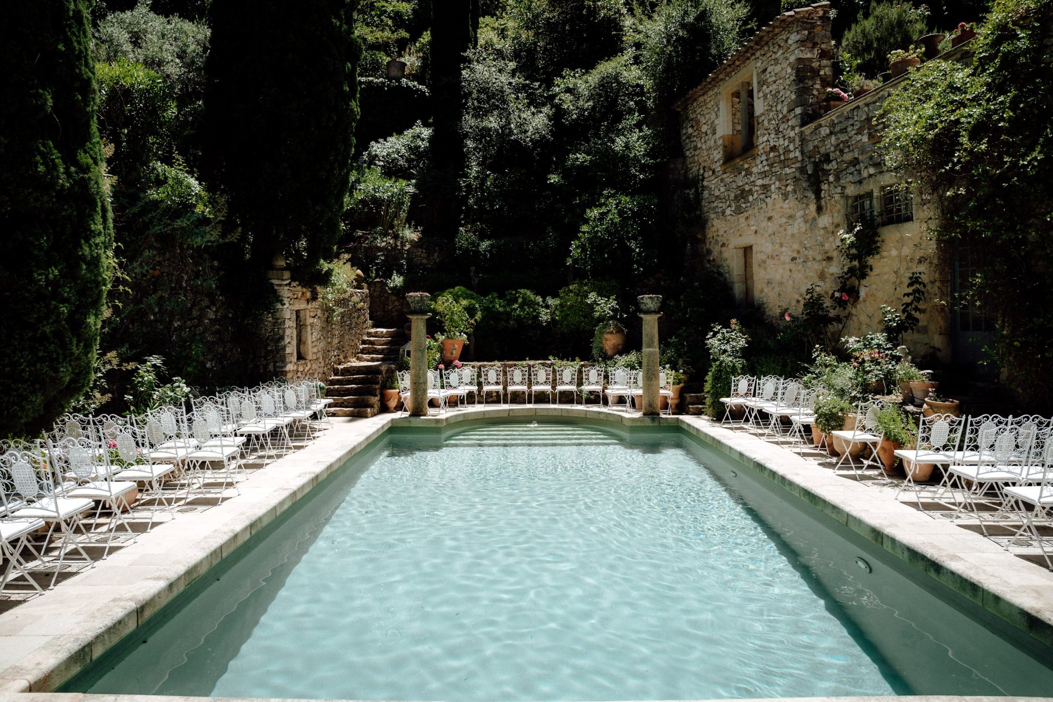 Long pool with rows of white chairs at Château St. Victor la Coste in Provence
