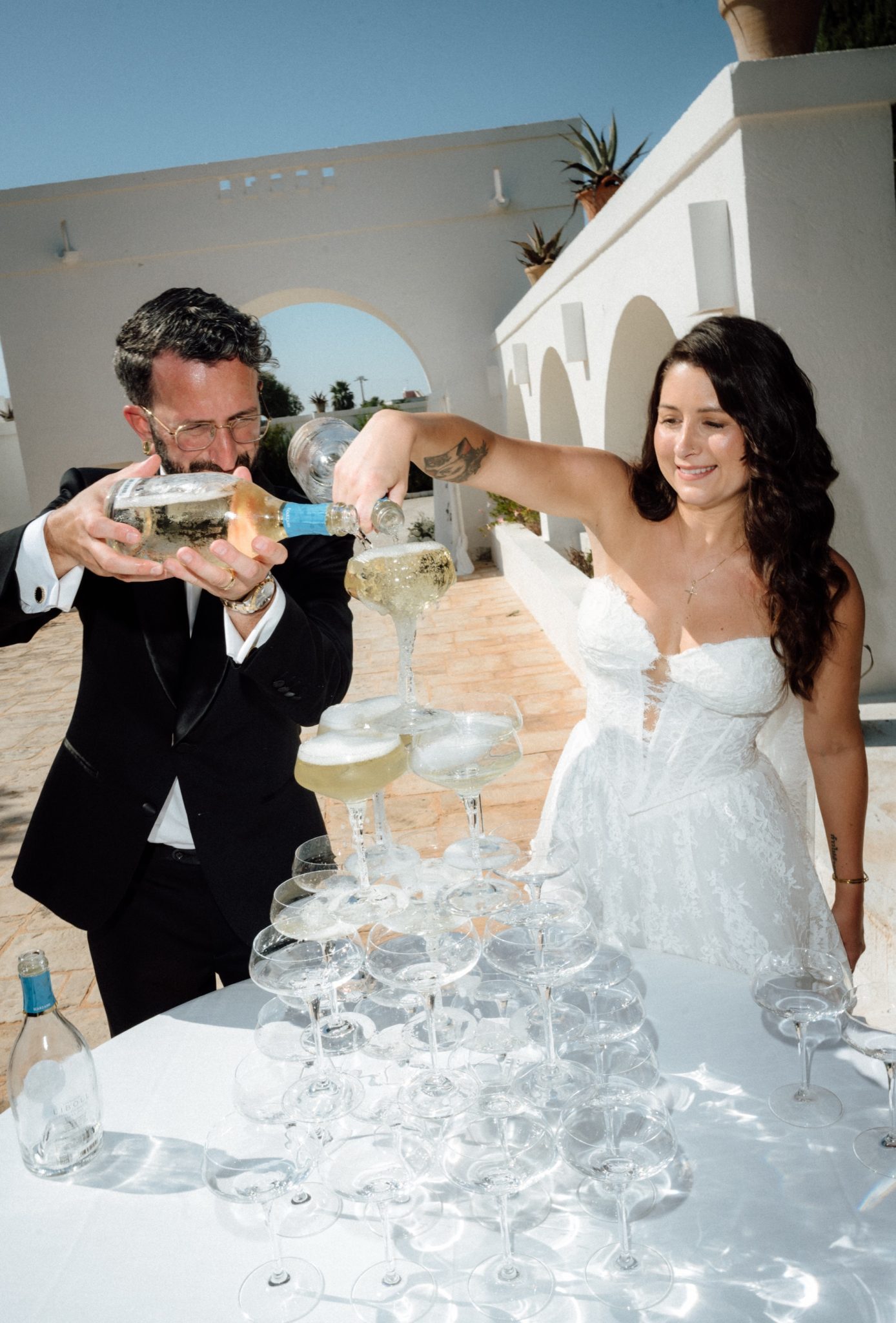 Bride and groom pouring champagne over a tower of glasses